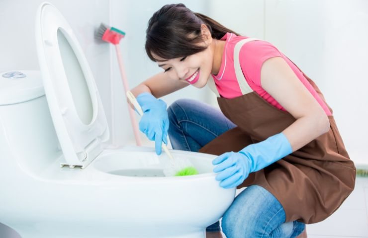 Ragazza sorridente svolge pulizie in bagno