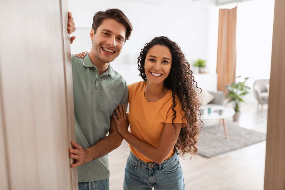 Giovane coppia sorridente sulla porta di casa